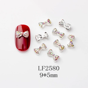 Détail du bijou d'ongle noeud strass AB 9x5mm sur une manucure rouge éclatante