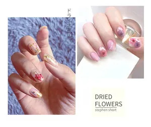 Detail of pink and purple dried flowers and gold foil embedded in nail art design