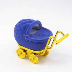 Close-up of deep blue velvet baby stroller jewelry box with gold metallic wheels