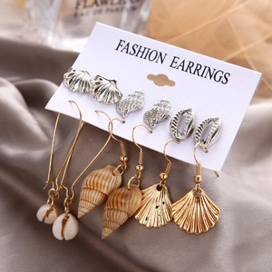 Detailed set of 6 pairs of gold ocean earrings with seashell and starfish charms on silk