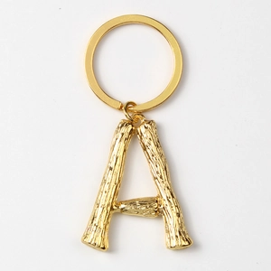 Macro detail of a gold letter A keychain with bamboo texture and polished metal ring