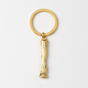Detailed view of golden metal keychain with textured branch pendant and round ring