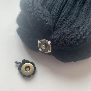 Black knit hat with a bronze snap button for a detachable faux fur pom pom