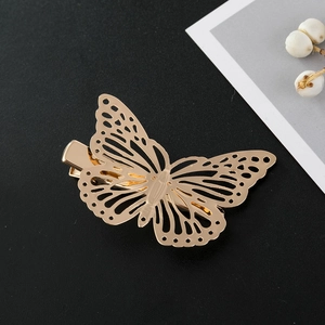 Close-up of a golden hollow butterfly hair clip on a minimalist dark textured background