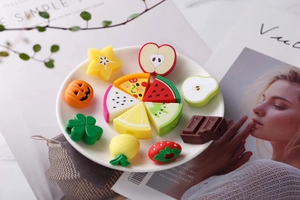 Detailed view of colorful fruit and food shaped silicone cable protectors on a white plate