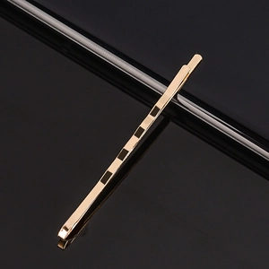 Barrette dorée minimaliste au fini métallique brillant sur fond noir réfléchissant
