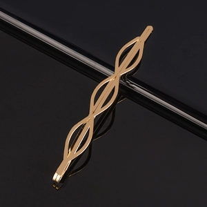 Barrette à cheveux minimaliste dorée avec un design ondulé sur fond noir brillant