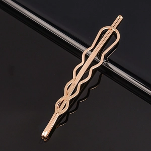 Pince à cheveux minimaliste en métal or rose avec design ondulé sur fond noir réfléchi
