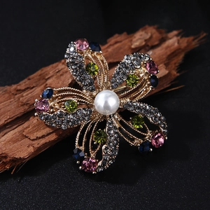 Luxurious floral crystal brooch with colorful gems and white pearl on vintage wood surface