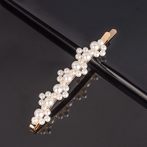 Macro detail of elegant gold-toned hair clip featuring cluster of white faux pearls