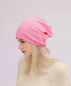 Vista laterale di un berretto in maglia rosa tenue indossato con maglieria invernale