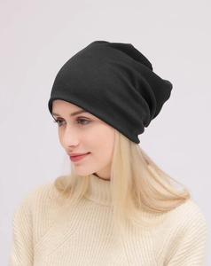 Dettaglio di un berretto nero in cotone lavorato a maglia con pieghe su un modello trendy