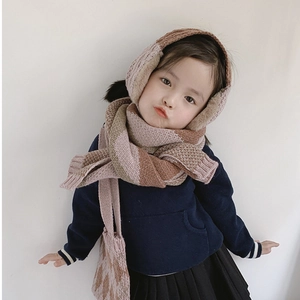 Detail of child wearing a gradient pink and brown knit scarf with earmuffs and matching bag