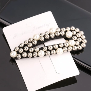 Detail of beaded hair clip with white faux pearls and silver studs on black fabric