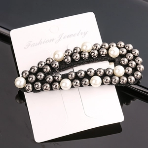 Detail of beaded hair clip with black metal studs and white pearls on display card