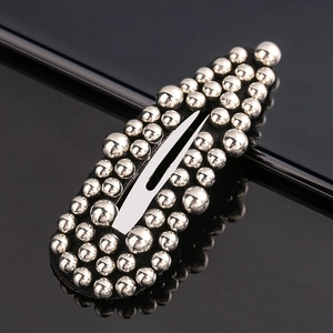 Detailed close-up of oval hair clip featuring dense silver metallic beads and metal base
