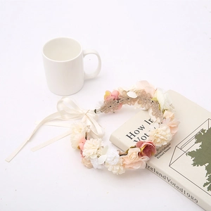 Detail of floral headpiece with pink silk flowers, lace, and white ribbons on a table
