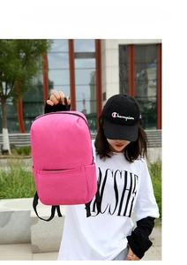 Detail view of a pink casual backpack featuring a front zipper pocket in a street setting