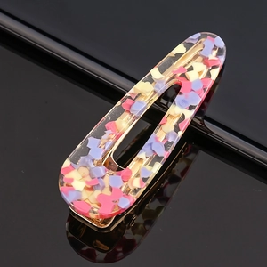 Macro shot of acetic acid hair clip with colorful geometric flakes and gold base