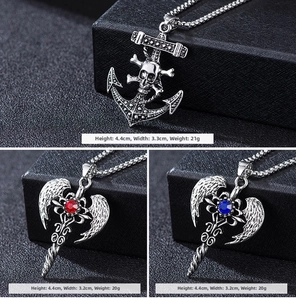 Detail of punk style skull anchor and angel wing pendants with red and blue gems