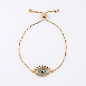 Detail of gold box chain bracelet featuring a blue cubic zirconia evil eye charm and slider