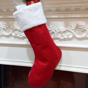 Calza di Natale rossa con bordo in finta pelliccia bianca appesa a un caminetto classico