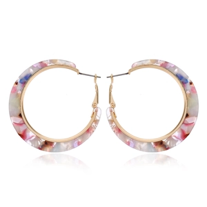 Detailed view of colorful tortoiseshell acetate earrings with a golden metal frame and reflection