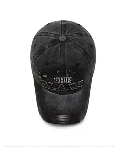 Macro detail of washed black baseball cap with embroidered text and brown leather brim edge