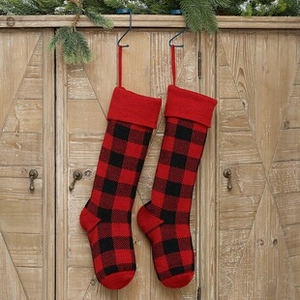 Detail of red and black buffalo plaid knitted Christmas stockings hanging on rustic wood