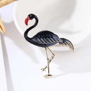 Close-up of flamingo brooch with black enamel finish and gold accents on white porcelain