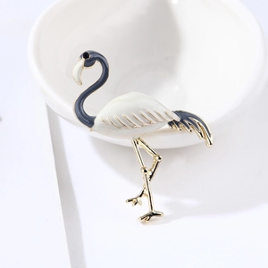 Detail of elegant gold flamingo brooch with white and blue enamel on white surface