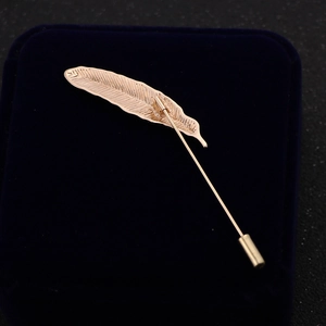 Elegant rose gold feather brooch pin for suits displayed on a blue velvet jewelry box