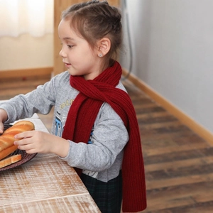 Winter warm knitted red scarf with thick ribbed texture worn by a child in grey hoodie