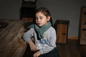 Detail of warm green knitted scarf paired with grey cotton hoodie for kids