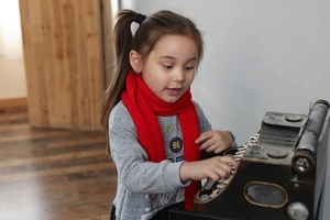 Close-up of a warm red knitted scarf worn by a girl playing a vintage toy piano