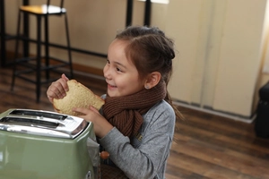 Close-up of a child wearing a cozy brown ribbed knit winter scarf in a warm kitchen setting