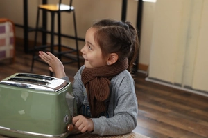 Close-up of a child wearing a cozy brown knitted scarf in a warm home kitchen setting