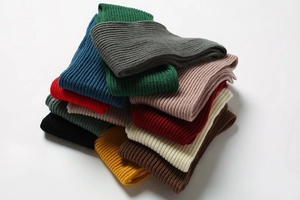 Close-up of stacked warm ribbed knit scarves in multiple solid colors for winter