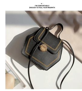 Detail of black faux leather pentagonal crossbody bag with gold stitching and lock