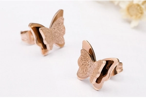 Detalle macro de pendientes de mariposa en oro rosa con acabado mate de doble capa