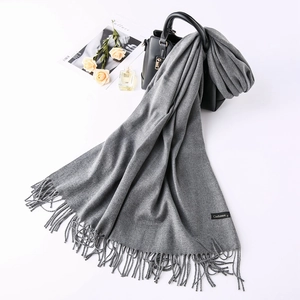 Flat lay of gray cashmere scarf with fringe, stylish accessories, and elegant props