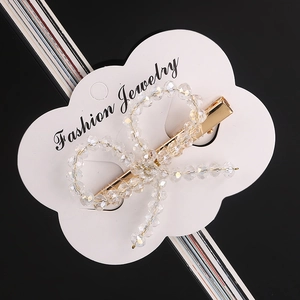 Detailed view of handmade crystal bead bow hair clip on cloud-shaped display card