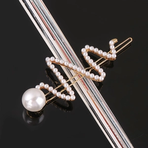 Macro detail of a gold hair clip with handmade woven design and large white pearls