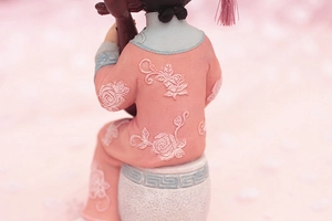 Detail of pink embroidered palace robe and blue trim on vintage doll figurine