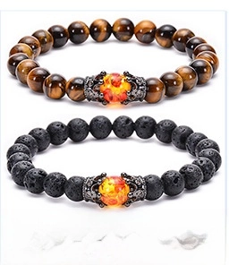 Detail of tiger eye and lava stone beaded bracelets with silver crown charms