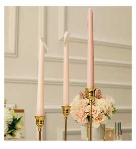 Pink tapered scented candles set with elegant gold metal holders on a classic background