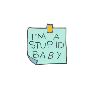 Macro detail of enamel pin shaped like a green memo with I'm a Stupid Baby text