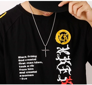 Close-up of titanium steel cross pendant on a model wearing a black graphic T-shirt