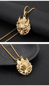 Detail of a golden wolf head pendant necklace with an intricate carved design on a box chain