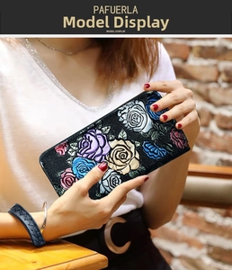 Close-up of model holding a long black leather wallet with colorful 3D embossed roses